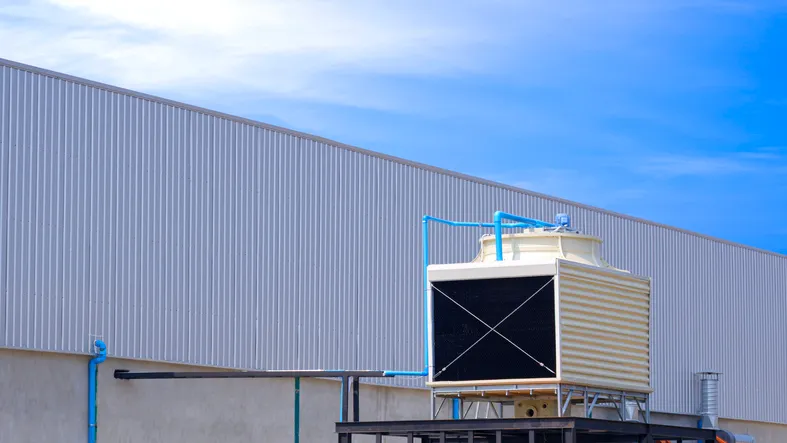Torre de enfriamiento cuadrada fuera del edificio de la fábrica sobre fondo de cielo azul