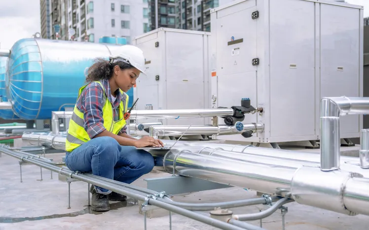 Una ingeniera inspecciona y controla el sistema de refrigeración del aire acondicionado de una gran fábrica.