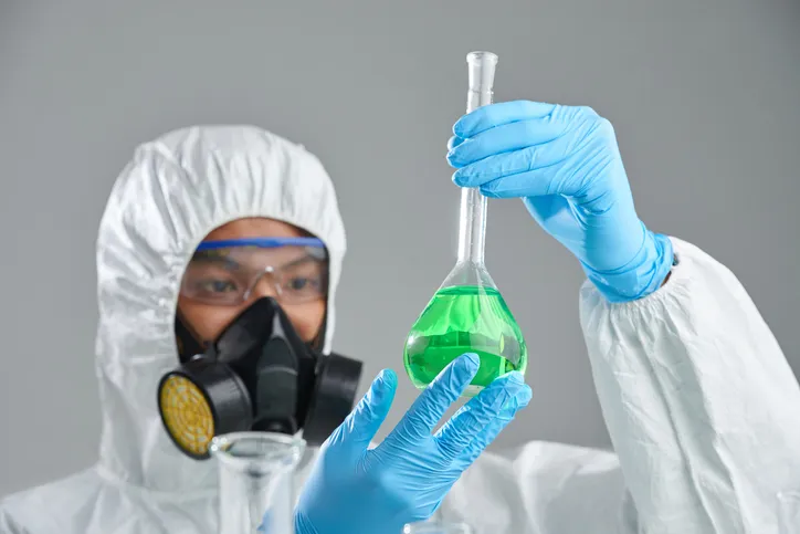 Químico con equipo de protección manipulando un matraz con liquido