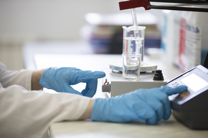 Manos de un qumico trabajando con una muestra de una sustancia corrosiva