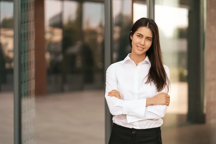 Mujer con blusa blanca afuera de una oficina