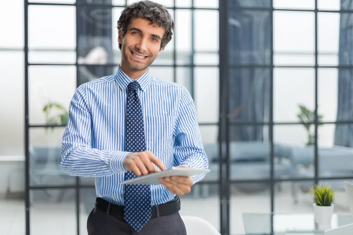 Hombre joven con camisa de vertir azull y corbata en oficina corporativa
