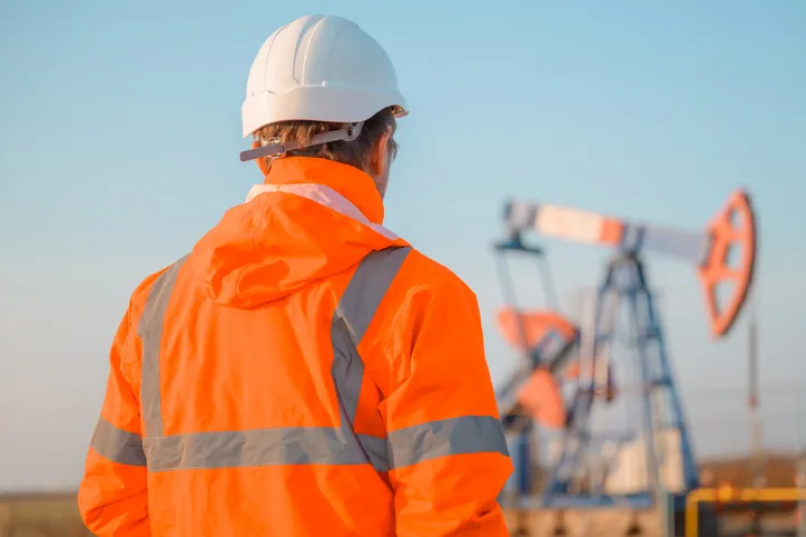 Ingeniero de plataforma de perforación que supervisa el proceso de extracción de petróleo y gas, con chamarra HI VIS