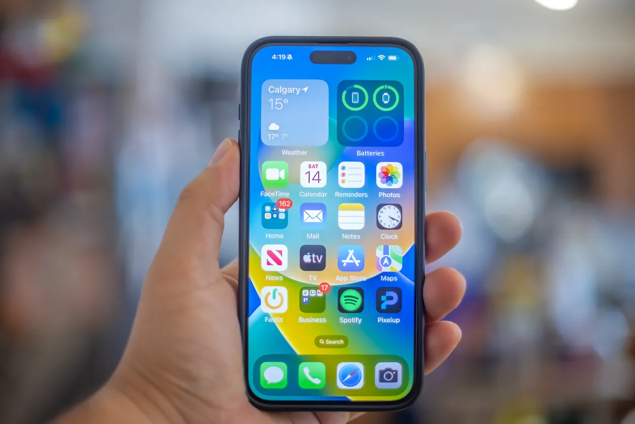 Una mano que sostiene un iPhone 15 Plus, un teléfono inteligente moderno negro que muestra una pantalla de inicio personaliza