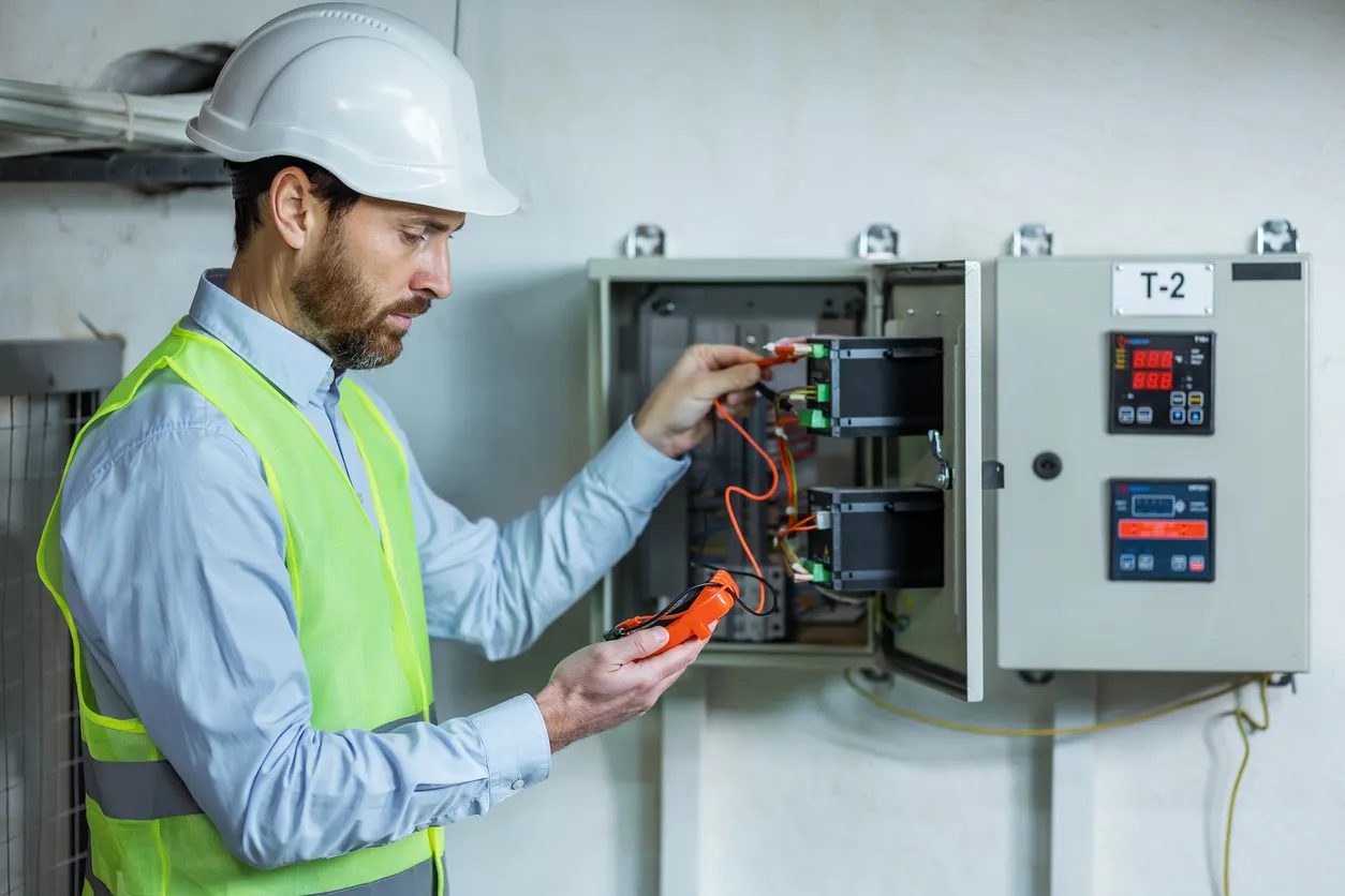 Un electricista trabaja en un gabinete eléctrico con un cable de conexión eléctrica.