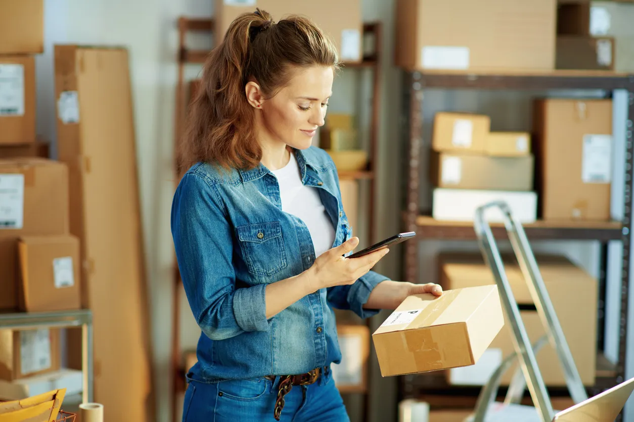 Mujer en almacén revisando su celular moderno, los cuales se han convertido en una herramienta esencial en los negocios. 