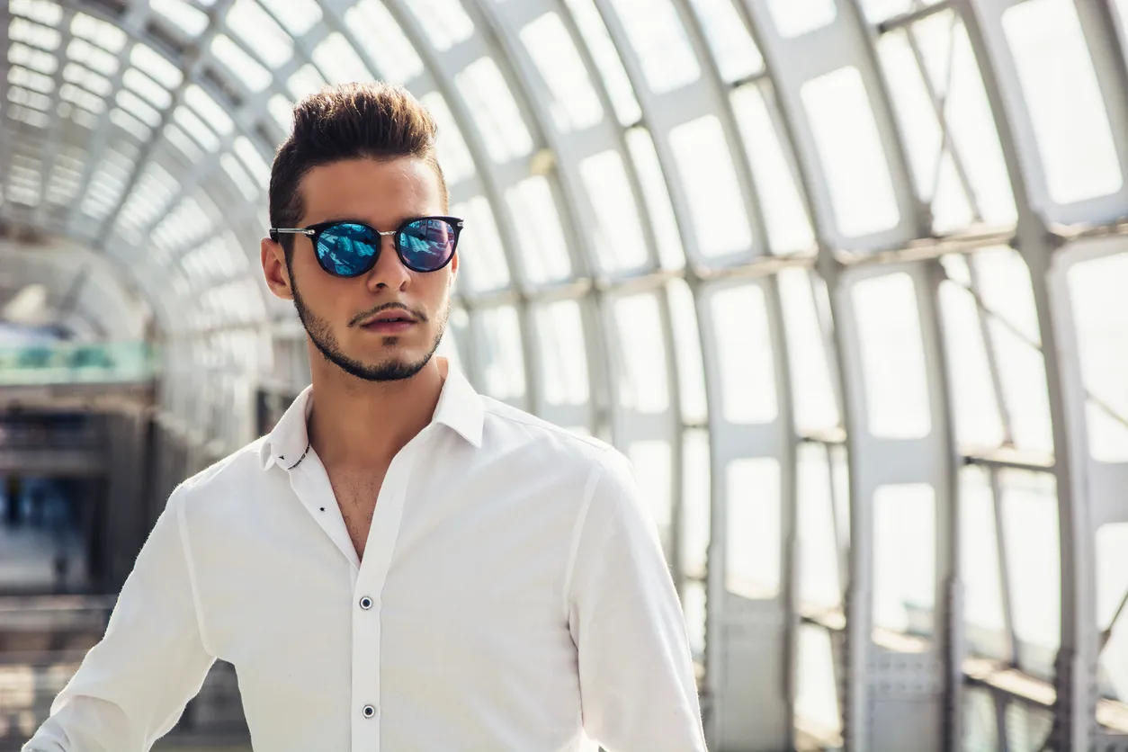 Hombre joven en la estación de tren con gafas de sol