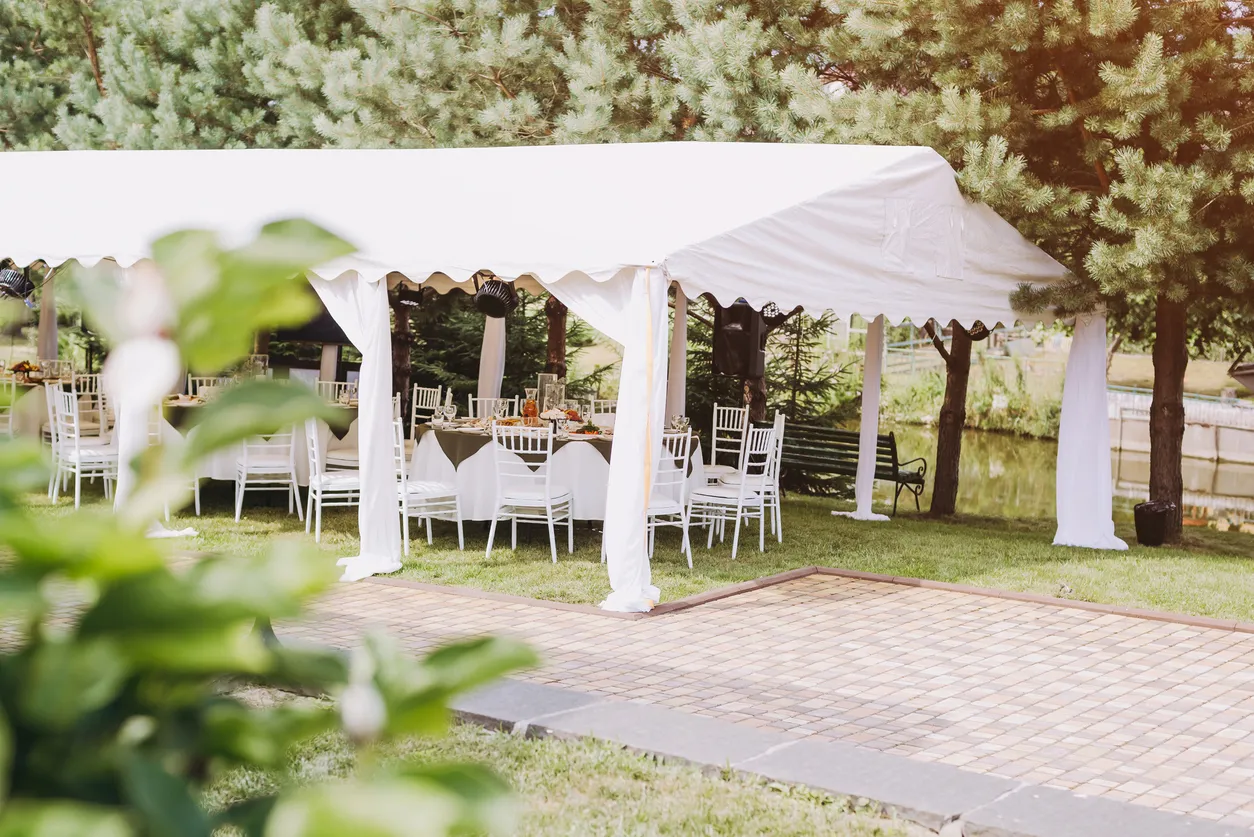Carpa con mesas y sillas ordenadas para un evento en un gran jardín. Aquí es posible el uso de enfriadores de aire.