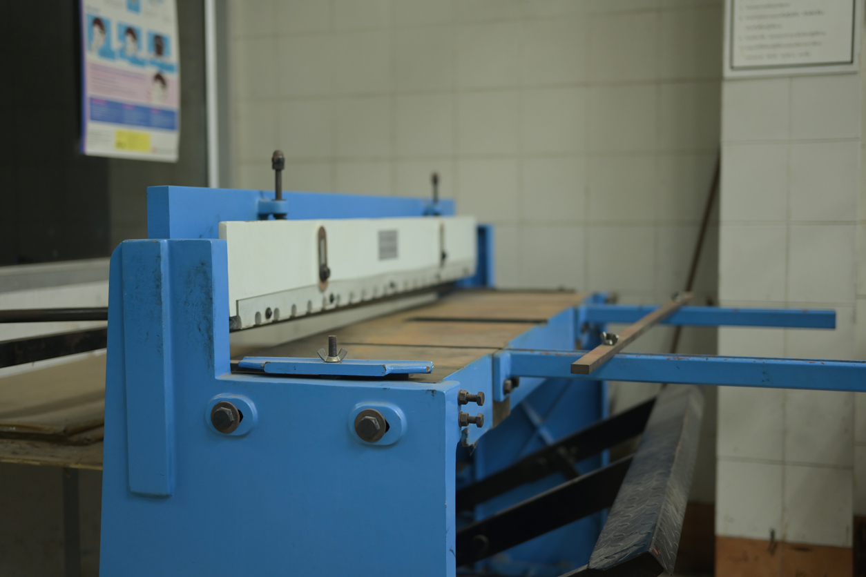 Una robusta cizalla de pie azul en un taller de grabado, diseñada para el corte preciso de papel y placas de metal 