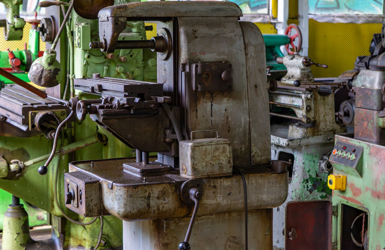 Fresadora antigua en un taller industrial, bien conservada y rodeada de otros equipos metalúrgicos