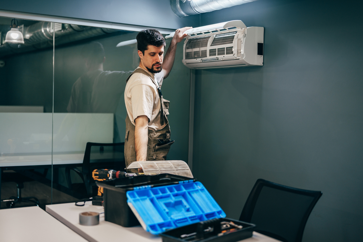 Un técnico instala una unidad de aire acondicionado en un espacio de oficina moderno durante el día