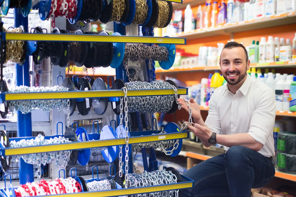 Hombre seleccionando una cadena metálica en una tienda de artículos para el hogar- La oferta y precios son esenciales.