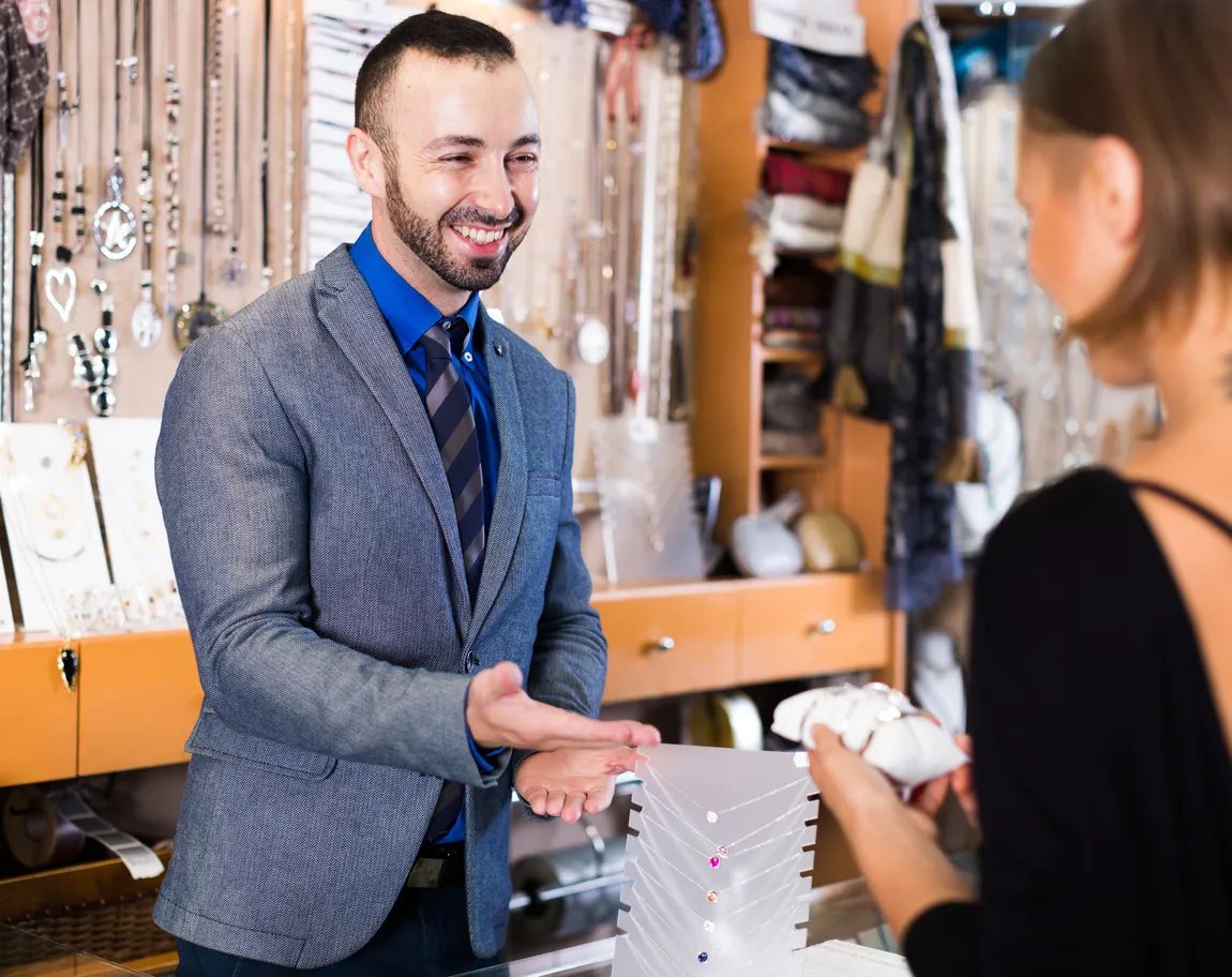 Vendedor trabajador mostrando diferentes colgantes en la joyería.