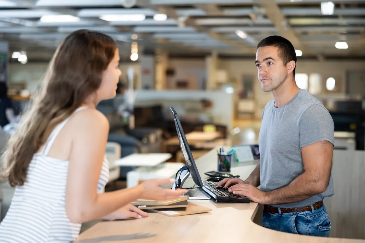 Vendedor de sala de exposición de muebles asesorando a una compradora sobre el surtido