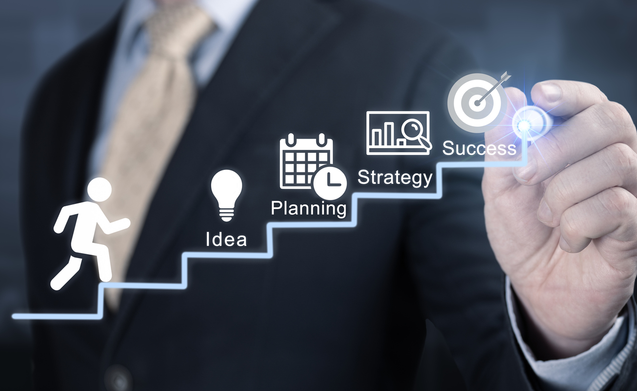 La mano del empresario dibuja la escalera hacia las metas de éxito, los pasos de la idea, la planificación, la estrategia. 