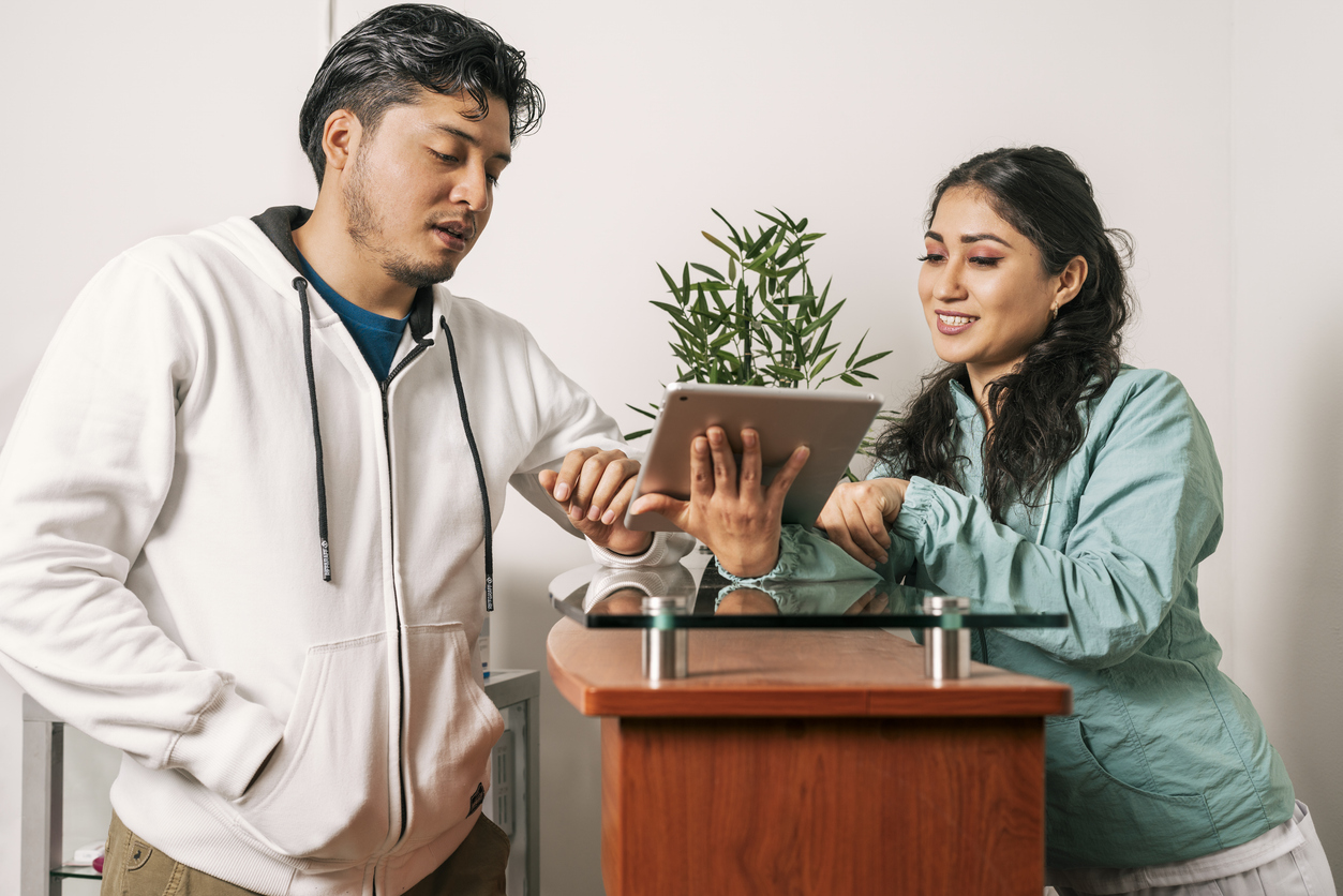 Recepcionista que atiende a un hombre que usa una tableta en una clínica dental