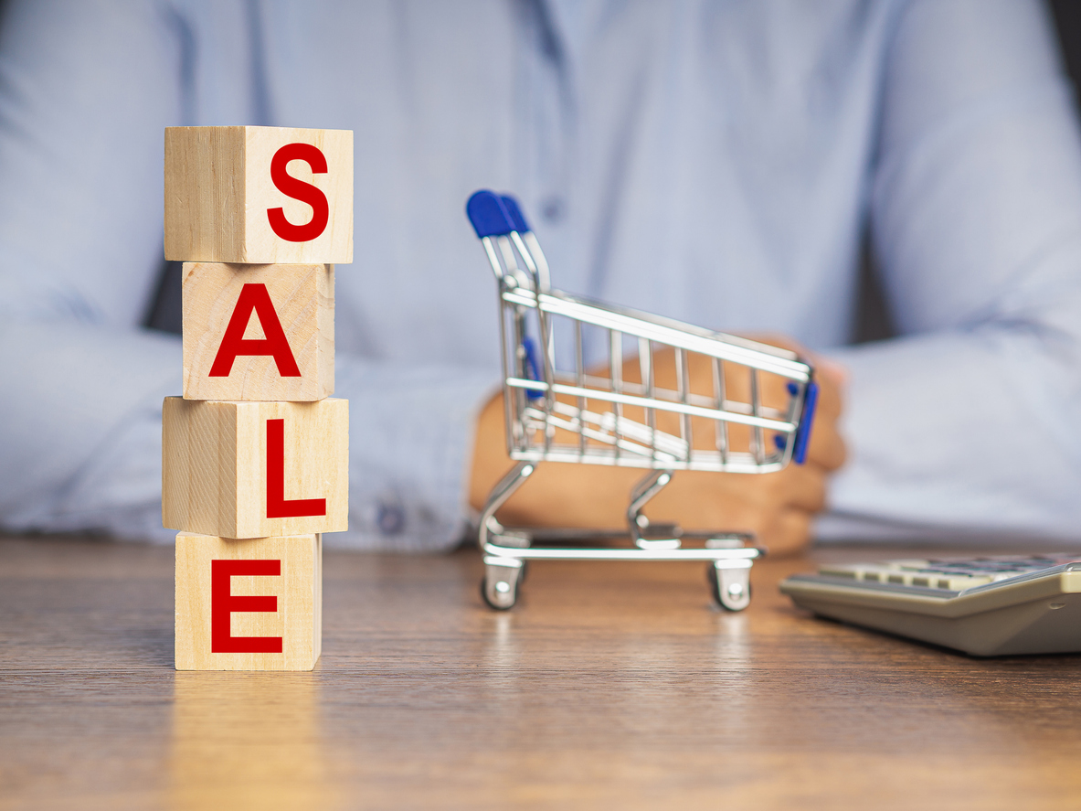 Cubos de madera con texto SALE y un mini carrito de la compra sobre una mesa de madera