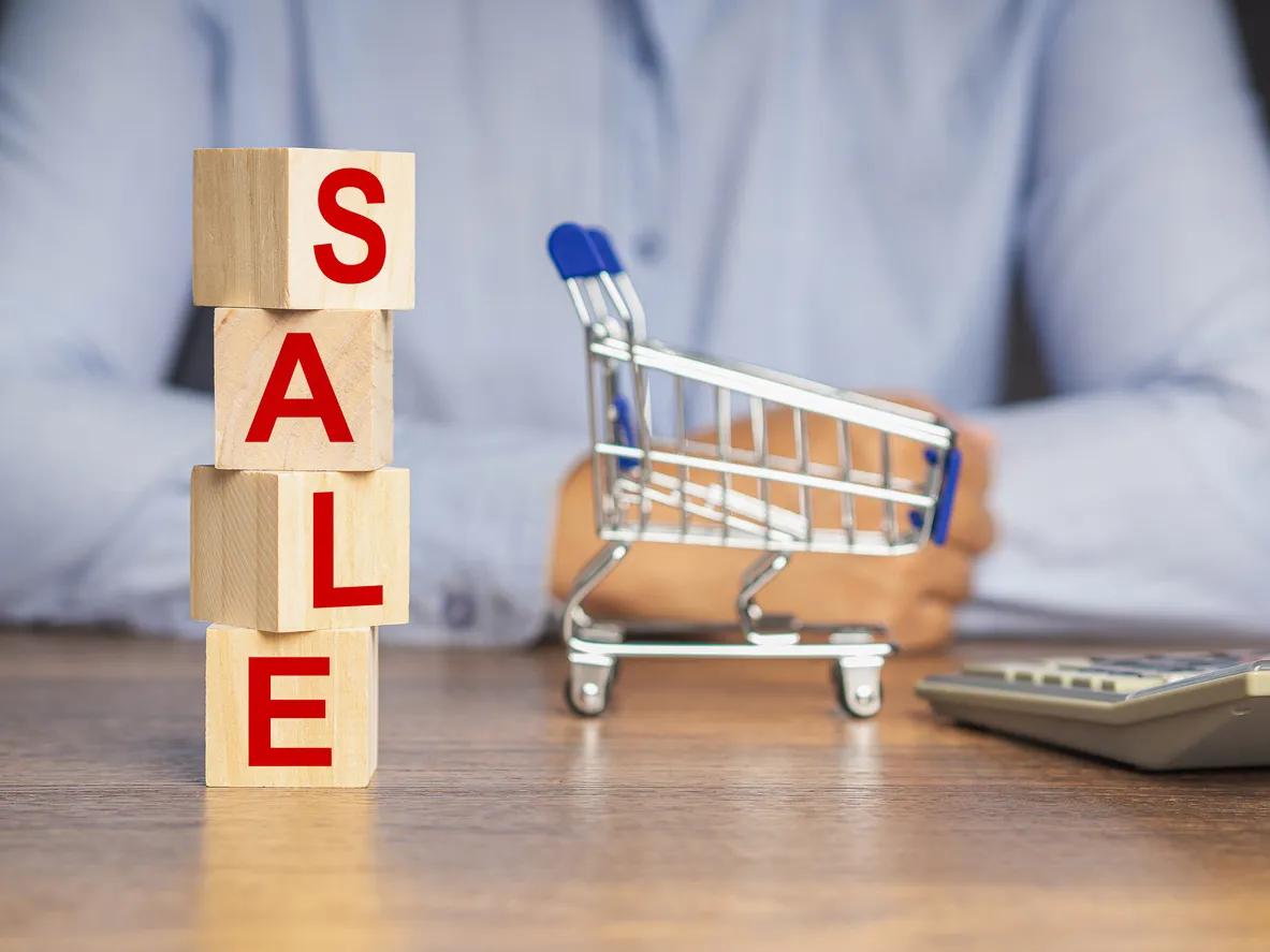 Cubos de madera con texto REBAJAS y un mini carrito de compras sobre una mesa de madera