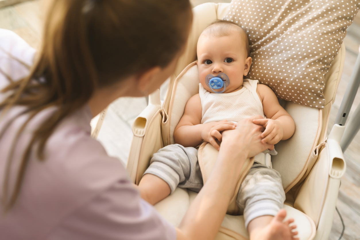 La madre pone al niño a dormir en la cuna eléctrica de los niños. La felicidad de la maternidad y el inicio de una familia