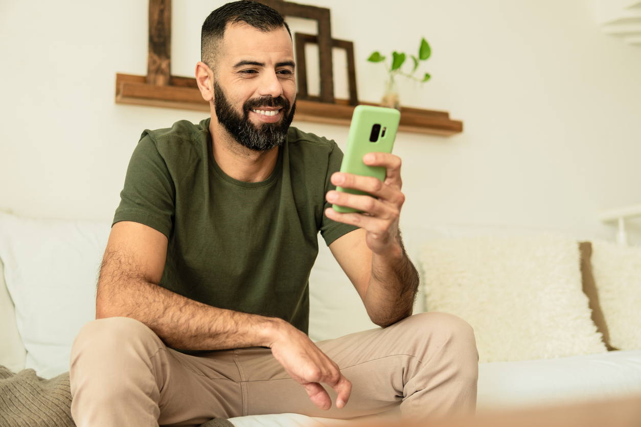 Hombre con amputación parcial de la mano sonriendo y mirando la pantalla del teléfono celular