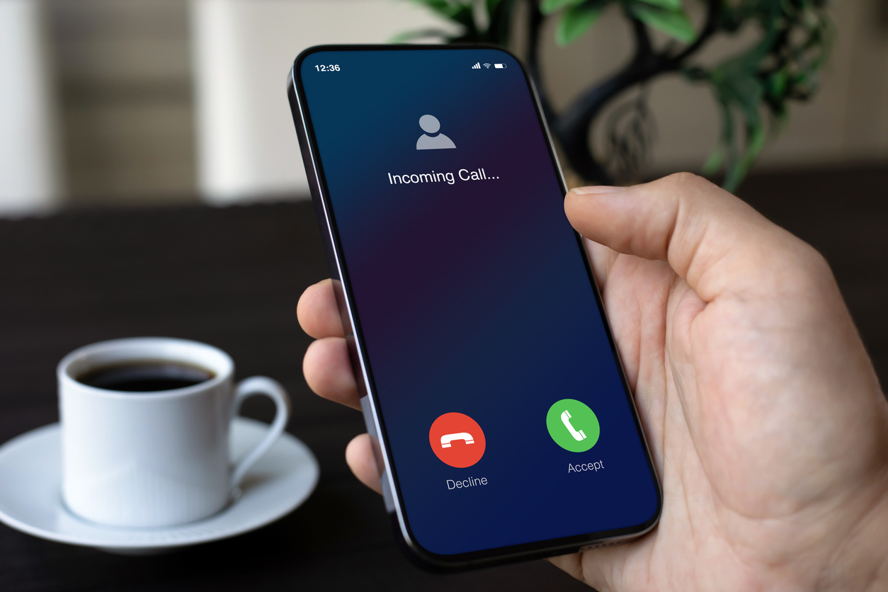 Teléfono masculino que sostiene la mano con la pantalla de llamada entrante en la oficina 