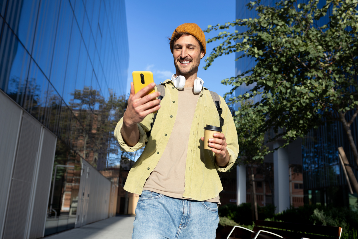 Joven sonriente usando un teléfono inteligente