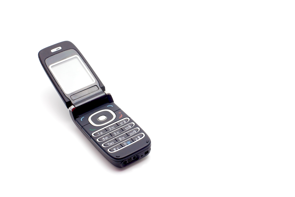 Joven feliz tirando el avión de papel mientras habla en el teléfono inteligente en azul 