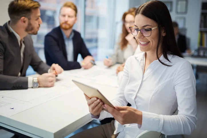 Mujer ejecutiva con uniforme corporativo en sala de reuniones con compañeros