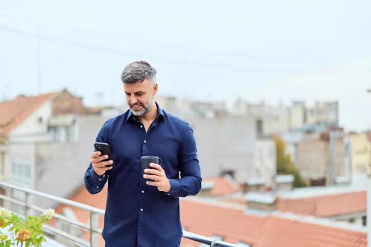 Hombre maduro con camisa azul marino y celular en mano