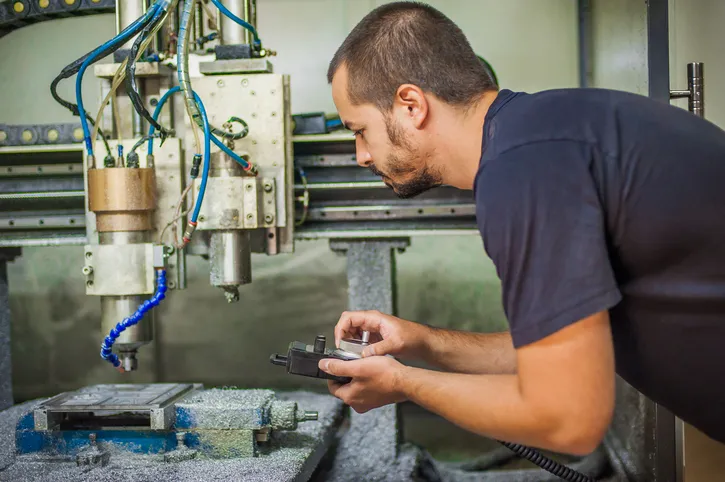 Ingeniero técnico trabajador que opera con la máquina de grabado de metal de fresado CNC