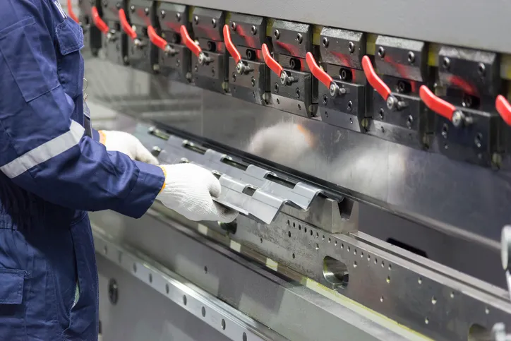 El operador técnico utilizando una dobladora de lámina