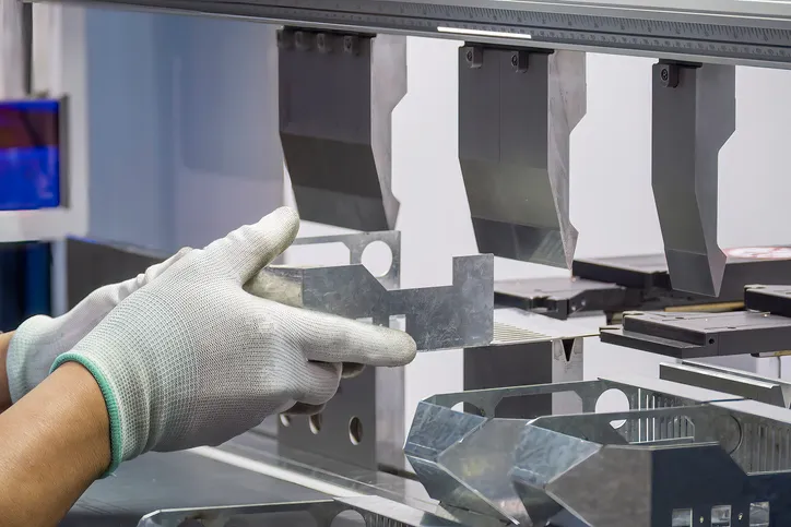 operador de la máquina dobladora sujeta las piezas de chapa metálica y use el guante de goma.