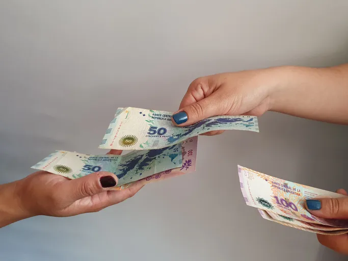 Manos de una persona dando dinero a otra