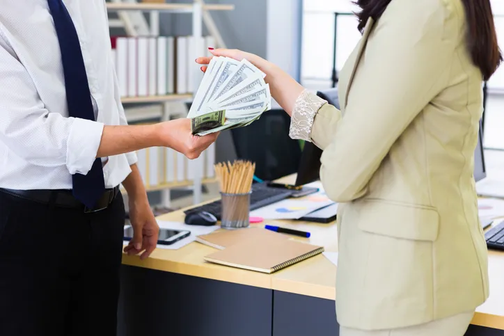 Empleado de oficina dando dinero a una trabajadora como anticipo de su nómina