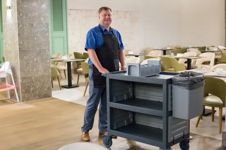 Un trabajador de un restaurante empuja un carrito para recoger platos sucios 
