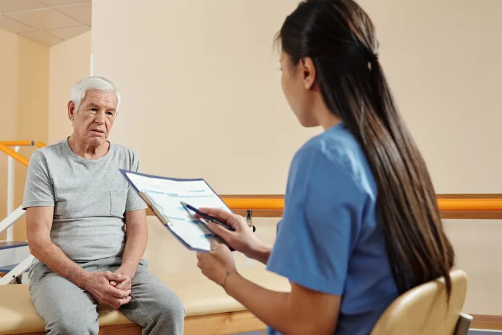 Hombre mayor escuchando a fisioterapeuta en el hospital