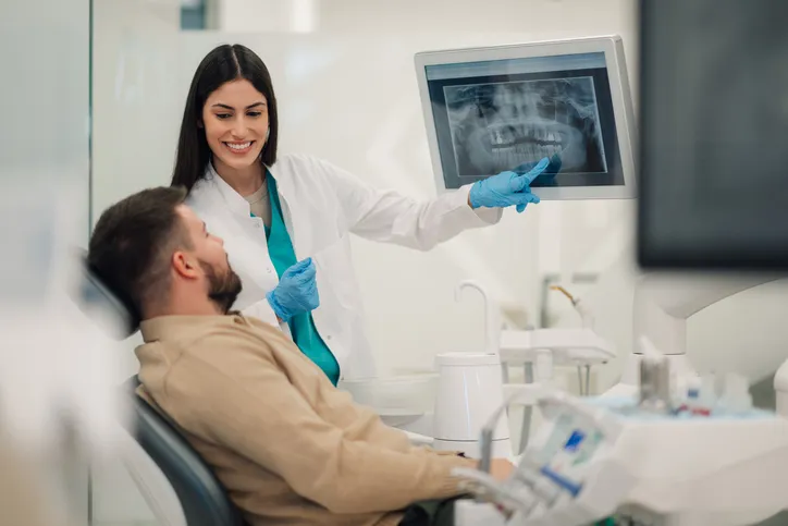 Dentista mostrando radiografía de dientes al paciente en una clínica moderna