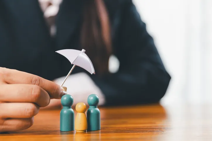 Manos que protegen el modelo de madera de la familia para el concepto de seguro y seguro de vida. 