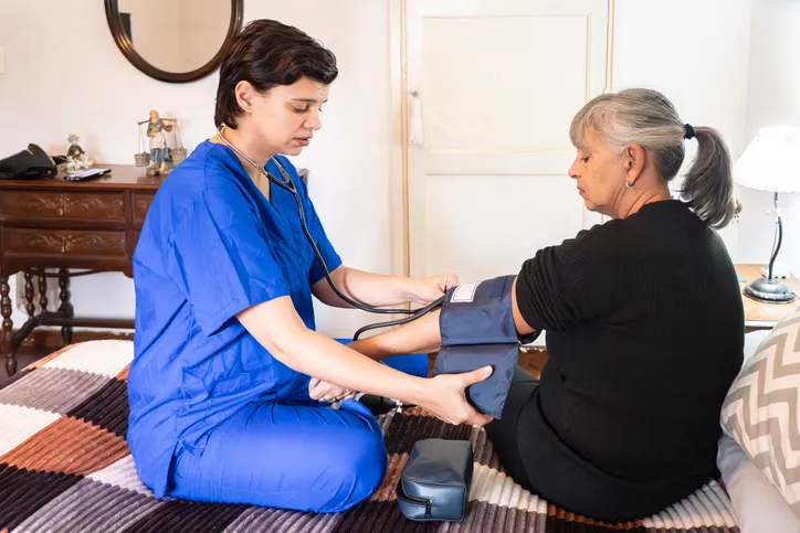 Control de la presión arterial de una mujer mayor durante una visita domiciliaria.