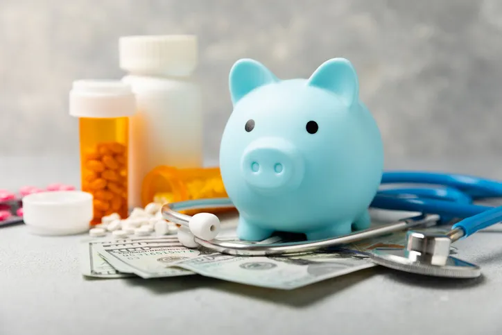 Costos médicos, concepto financiero, seguro médico. Estetoscopio sobre billetes de dólar. Dinero y alcancía.