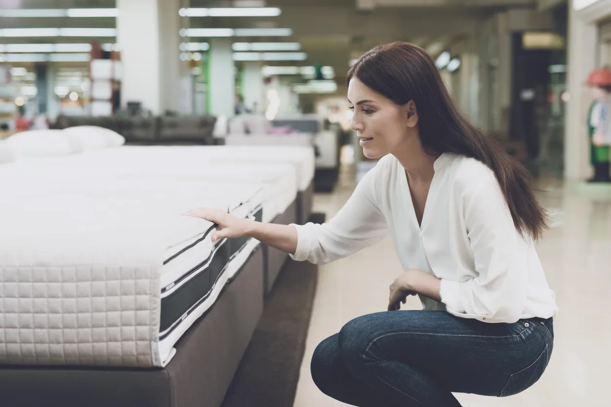 Mujer revisando colchón en tienda de muebles. Colchón hotelero matrimonial