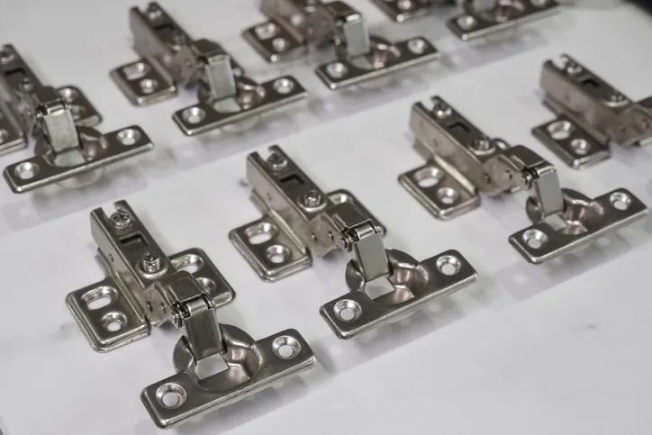 bisagras metálicas de armario dispuestas sobre una superficie blanca. 