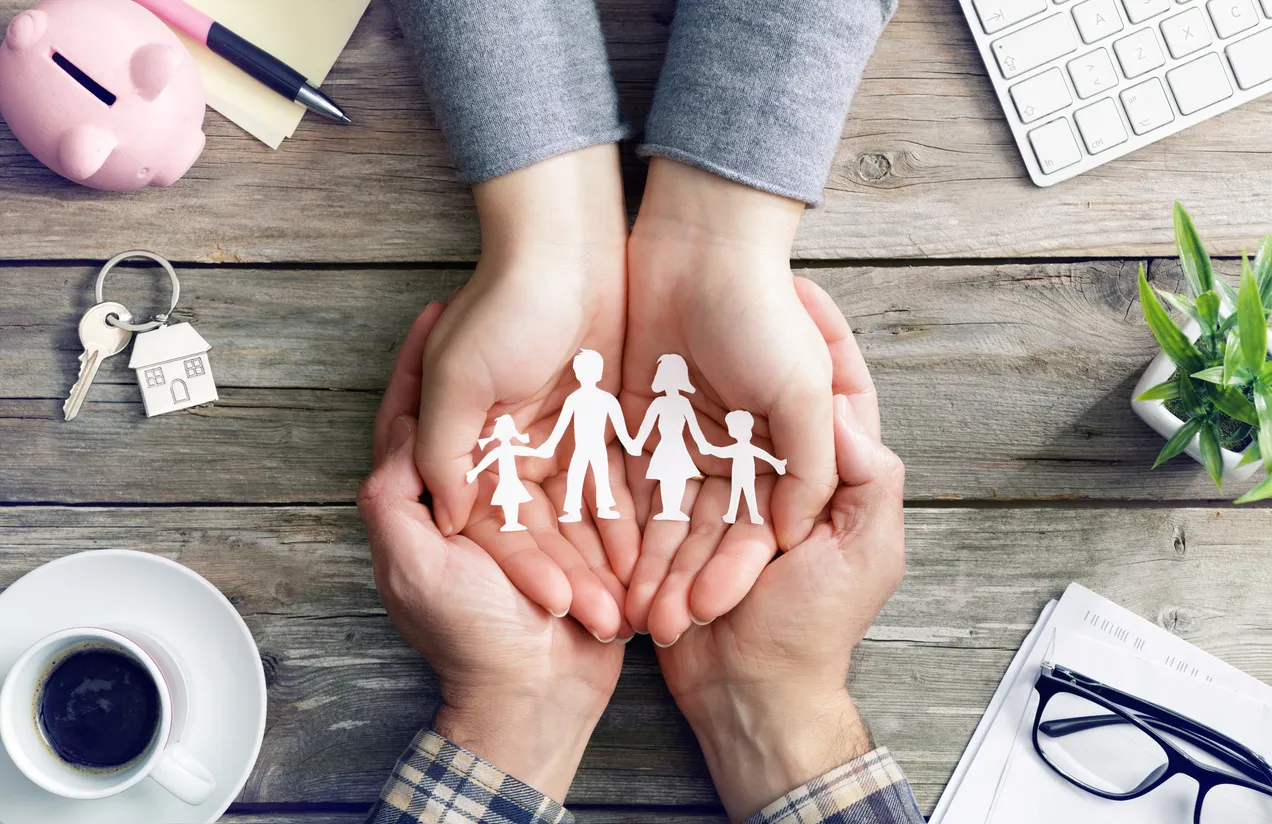 Representación del seguro de vida con las manos unidas de dos personas y entre ellas la representación de un familia