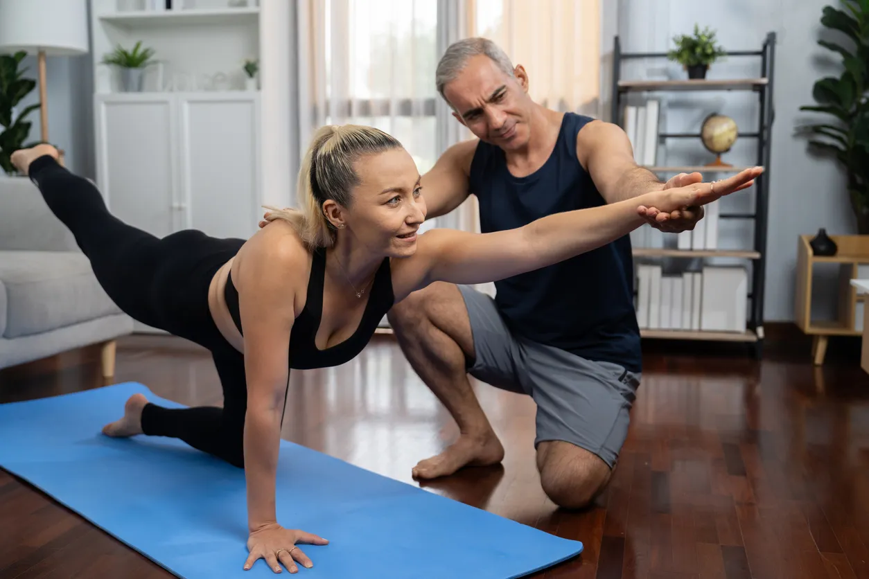 Entrenador personal con mujer adulta entrenando en casa
