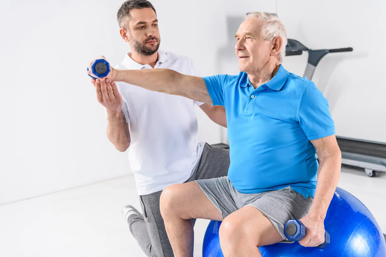 Hombre adulto mayor  con entrenador personal realizando ejercicio