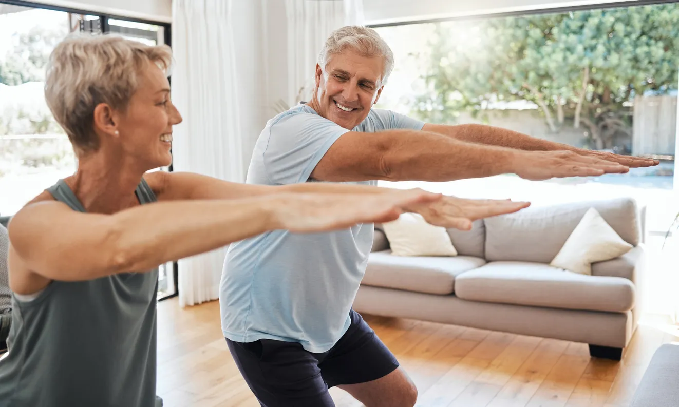 pareja de adultos mayores realizando ejercicio en la sala de su casa