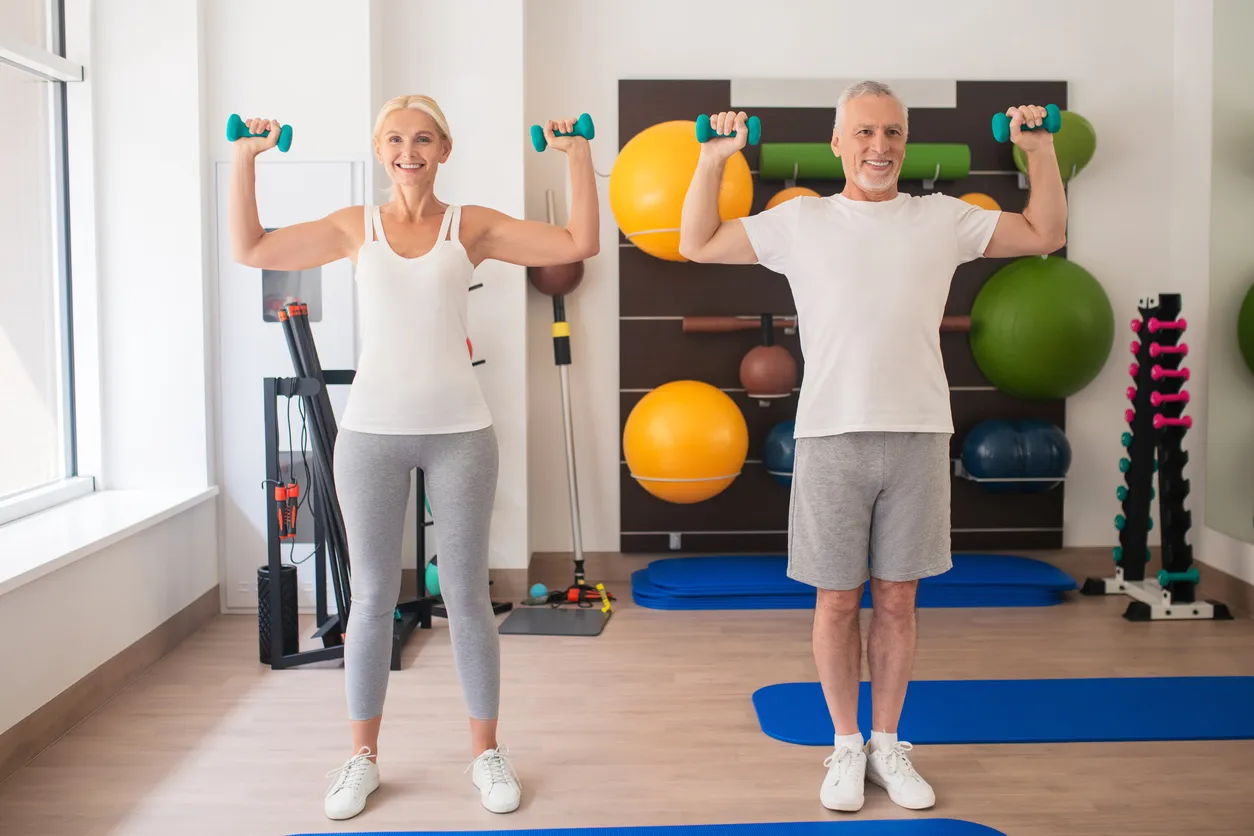 Entrenador con mujer adulta realizando ejercicio con pesas ligeras