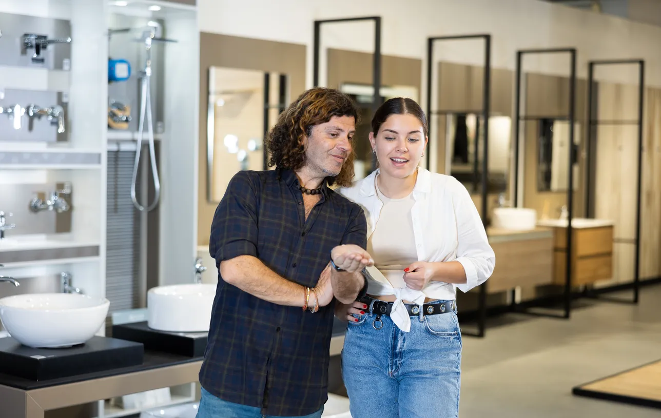 Pareja en sala de exhibición con un distrubuidor de muebles de baño comprando para su negocio.