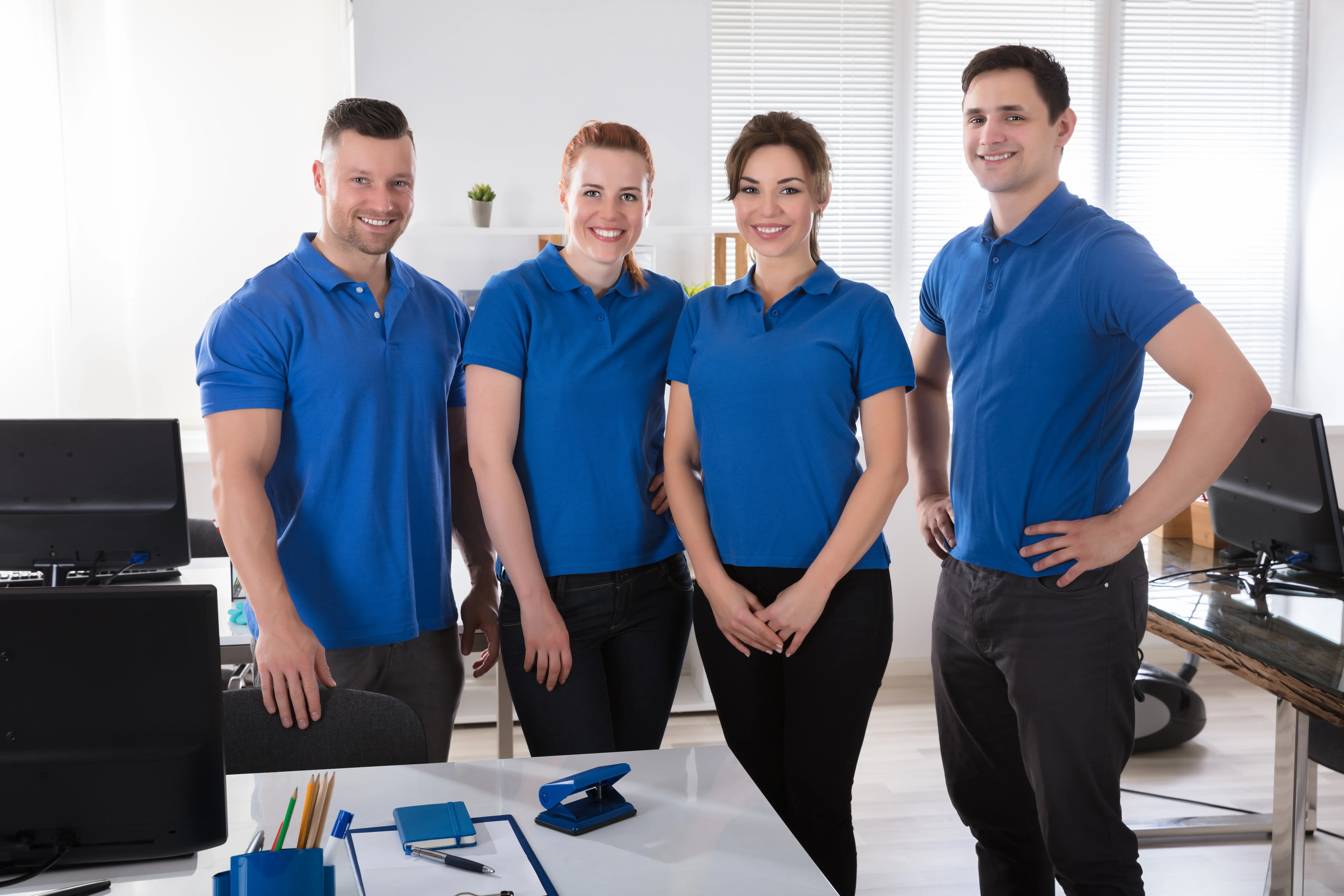 Grupo de personas con playera tipo polo  azul en una oficina. Las playeras son parte de uniformes empresariales