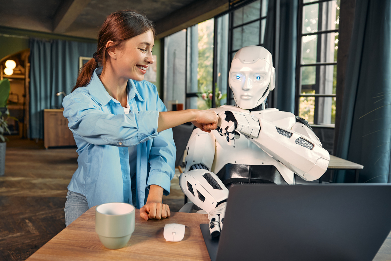 Robot and woman working on laptop in office 